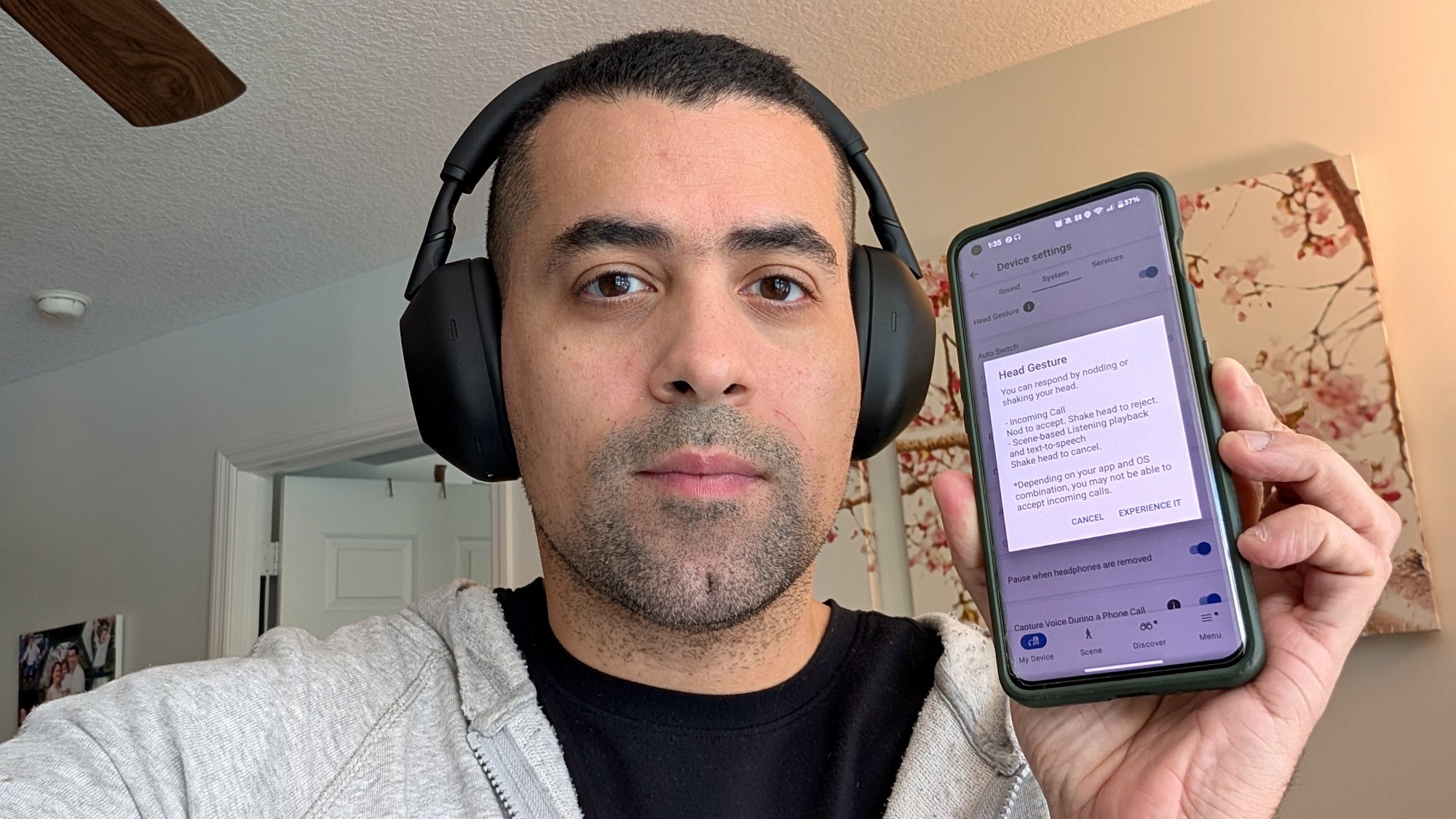 Penulis mengenakan headphone dan memegang telepon dengan pengaturan gerakan kepala di layar