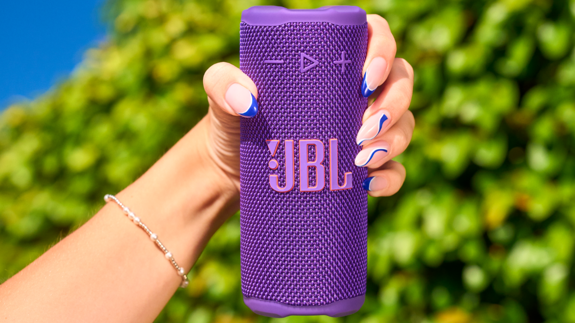 tangan wanita memegang speaker genggaman JBL ungu